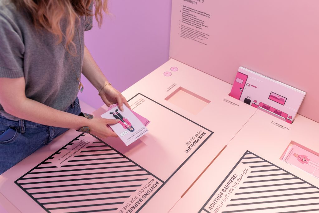 A person plays with cards in the interactive exhibit in the pink portal of the Innoklusio exhibition.